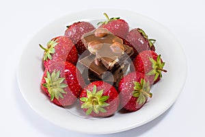 Plate full of tasty juicy strawberries and chocolate isolated on black background. Temptaion dieting summer slimming red berry bea
