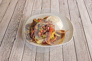 Plate full of typical Peruvian lomo saltado recipe accompanied by rice, peppers and red onion and homemade chips