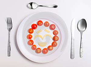 Plate with funny emoticons made from food with cutlery on white