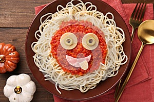 Plate with funny monster made of tasty pasta served on wooden table, flat lay. Halloween food