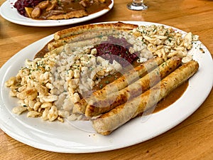 A plate of German food with chicken bratwurst sausages, potatoes and Red Cabbage