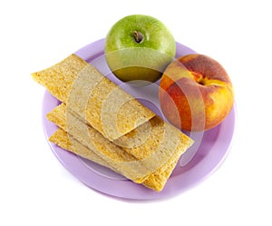 A plate with green apple, peach and three crisps