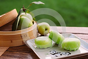 A plate of green apples and a basket of apples on a table. Mochi asian dessert