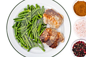 Plate with green beans and meat on white background, top view