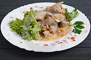 Plate of grilled beef nuggets, fried potato chips or French fries and fresh leafy green salad with cucumber on a white background