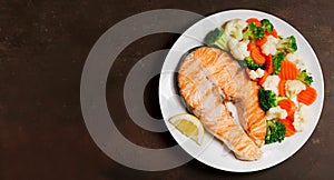 Plate of grilled salmon steak with vegetables, top view