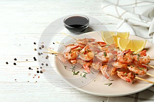 Plate with grilled shrimps on white wooden background