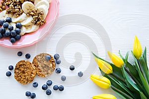 A plate of healthy breakfast, cookies, bananas and blueberry in white wooden background