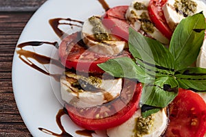 Plate of healthy classic delicious caprese salad with tomatoes and mozzarella cheese with fresh basil leaves on light linen