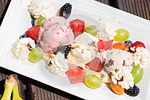 Plate of healthy fresh fruit salad with ice cream on the wooden background. Top view