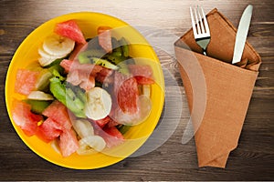 Plate of healthy fresh fruit salad on wooden background