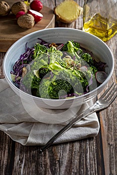 Plate with a healthy vegetarian salad of steamed broccoli, fresh radishes, walnuts, red cabbage, ginger and extra virgin olive oil photo