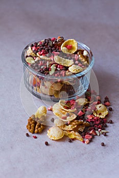 Plate of homemade muesli with cornflakes, freeze dried strawberry, walnuts, chocolate balls, pumpkin seeds