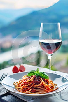 A plate of Italian spaghetti with tomato sauce, and a glass of red wine