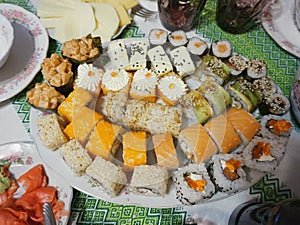 Plate with japanese sushi rolls on the table. Cloth with the Ukrainian ornament `vyshivanka`.