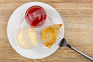 Plate with ketchup and mayonnaise and cheburek strung on fork
