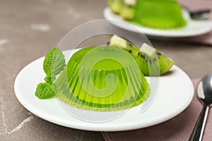 Plate with kiwi jelly and mint served on beige table