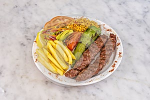 Plate of kofta kebab with roasted peppers, tomato chips