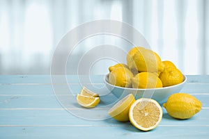 Plate with lemons on blue wooden table over abstract background