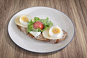 Egg And Cheese Sandwich With Lettuce And Cherry Tomato Served On Porcelain Plate Set On Walnut Wood Surface