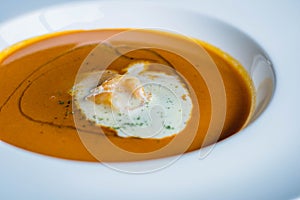 A plate of lobster bisque decorated with a dollop of cream and small shrimps