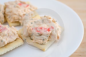Plate of lobster dip on saltine crackers on wood table