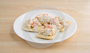 Plate of lobster dip on saltine crackers on a wood table