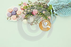 plate of macaroons over wooden table cofee and flowers.