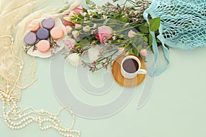 plate of macaroons over wooden table cofee and flowers.