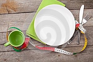 Plate with measure tape, cup, knife and fork. Diet food on woode