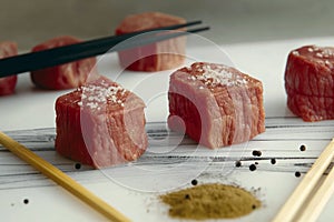 A plate of meat with chopsticks and a sprinkle of salt and pepper