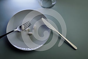 plate with medicine pills, fork and knife - concept for food problems, drug abuse, chemical feeding