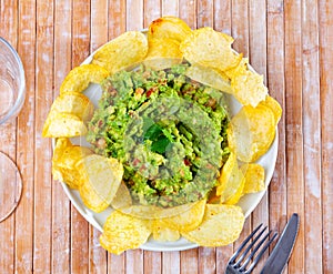 Plate of mexican chips with guacamole and glass beer closeup