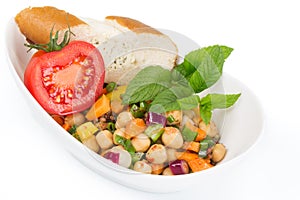 Plate of mixed salad with a sliced tomato and a piece of bread,