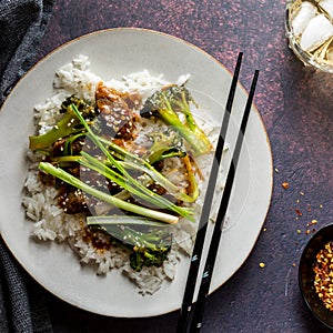 A plate of Mongolian Beef served with greens and rice, ready for eating.