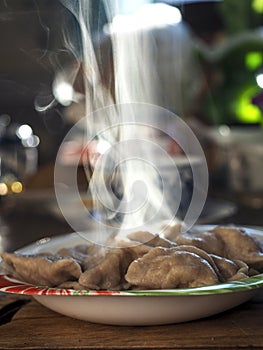 a plate of mouth-watering hot dumplings, steam rises above the plate