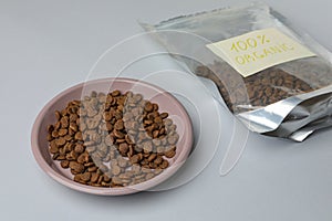 Plate and pack of organic kibble on light background