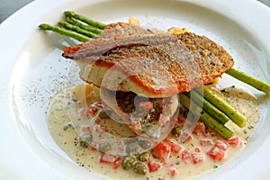Plate of pan seared sea bass with tomato caper mustard cream sauce