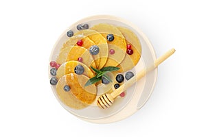 Plate with pancakes, dipper honey and berries isolated on white background