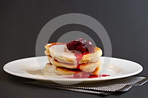 Plate with pancakes with sour cream and cherry syrup
