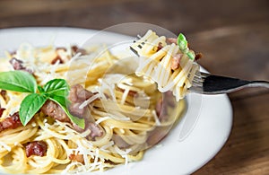 Plate of Pasta Carbonara and Spaghetti with bacon and parmesan cheese on a fork on old wooden table