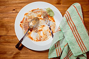 Plate of pasta with sauce finished and dirty on a wooden table