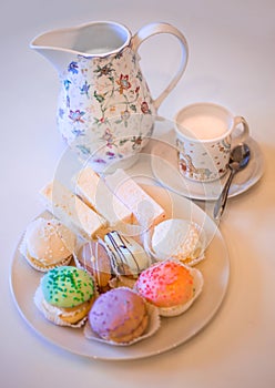 A plate of petits cakes with a cup and a jug.