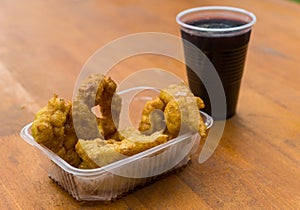 A plate of picarones with chicha morada at a street food market festival.