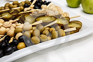 A plate of pickles on a buffet table. Selection of marinated mushrooms, salted cucumbers, olives, mustard in beans