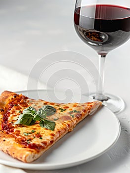 Plate with piece of cheese pizza and glass of red wine.