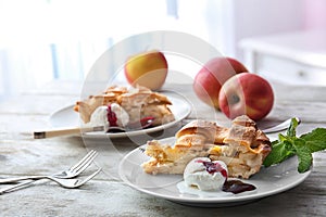 Plate with piece of delicious apple pie and ice-cream on wooden table