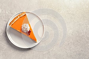 Plate with piece of fresh delicious homemade pumpkin pie on gray background, top view