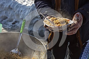 Plate with pilaf in male hands. Street food. Help for homeless