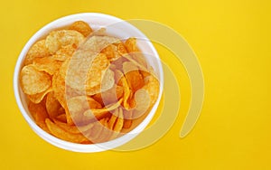 Plate with potato chips on a bright yellow background